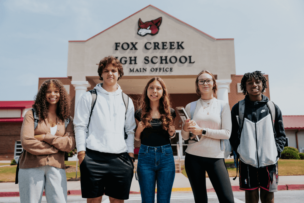 a group of students standing in front of a fox creek high school building