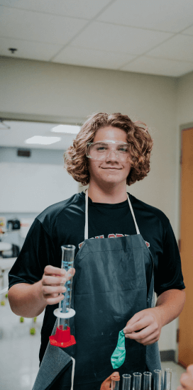 a student wearing a black shirt and apron holding a test tube